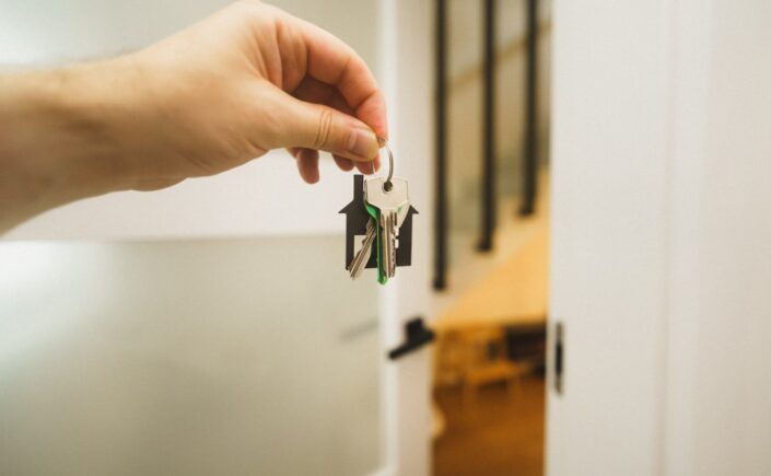 Person's hand holds a sleek, modern house key against a bright, clean background, symbolizing a new and simplified approac...