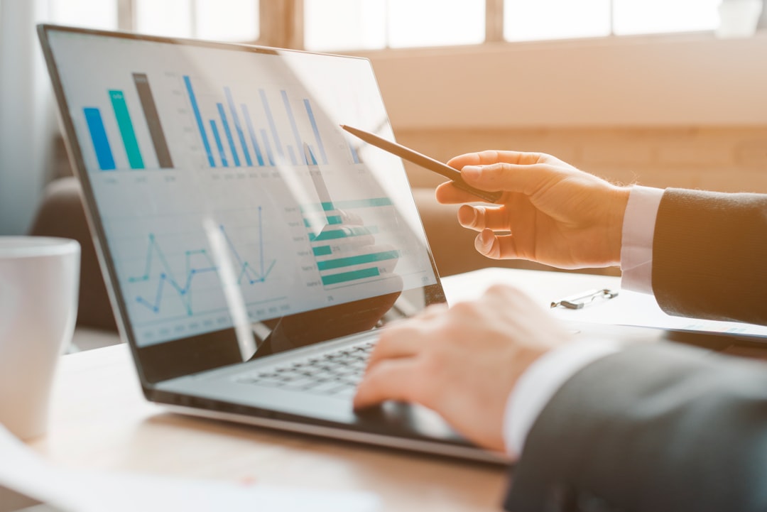 A marketing professional intently analyzes data on a laptop screen in a modern office, symbolizing a data-driven approach to selling a Florida home.