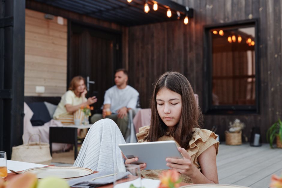 A woman thoughtfully reviews her property's marketing performance on a tablet while relaxing on the patio of a modern Florida home.
